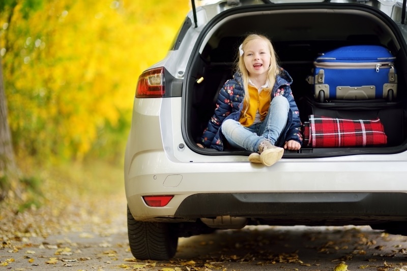 child with suitcases in the back cargo area of the car